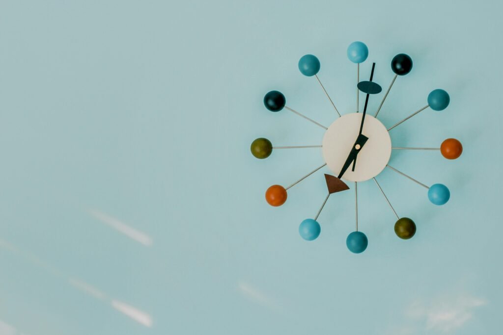 Close-up of a colorful modern wall clock on a blue background.